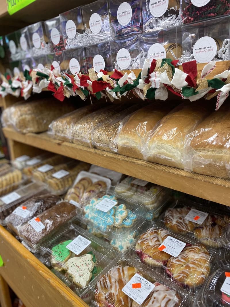 Bakery shelves: loaves of bread, cookie trays and bags of holiday treats tied with red and green ribbon.