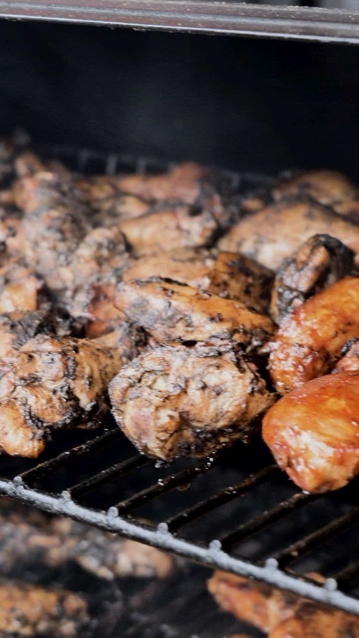 Charred chicken pieces cooking over the grill.