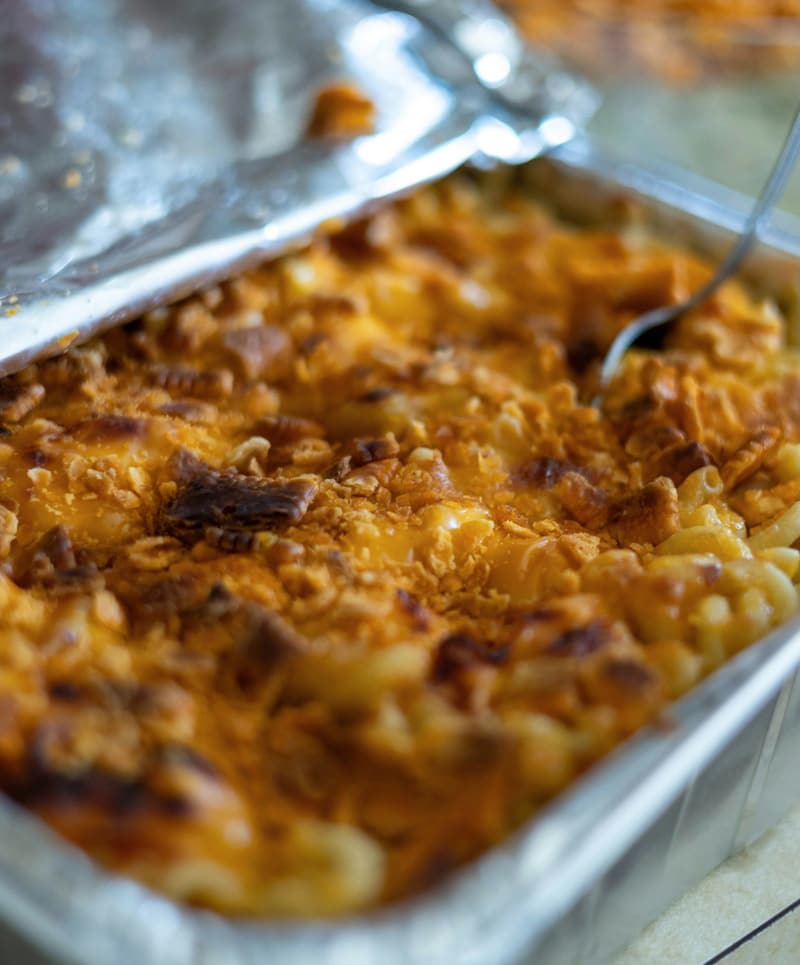 Baked mac and cheese with a golden crumb crust in a foil pan.