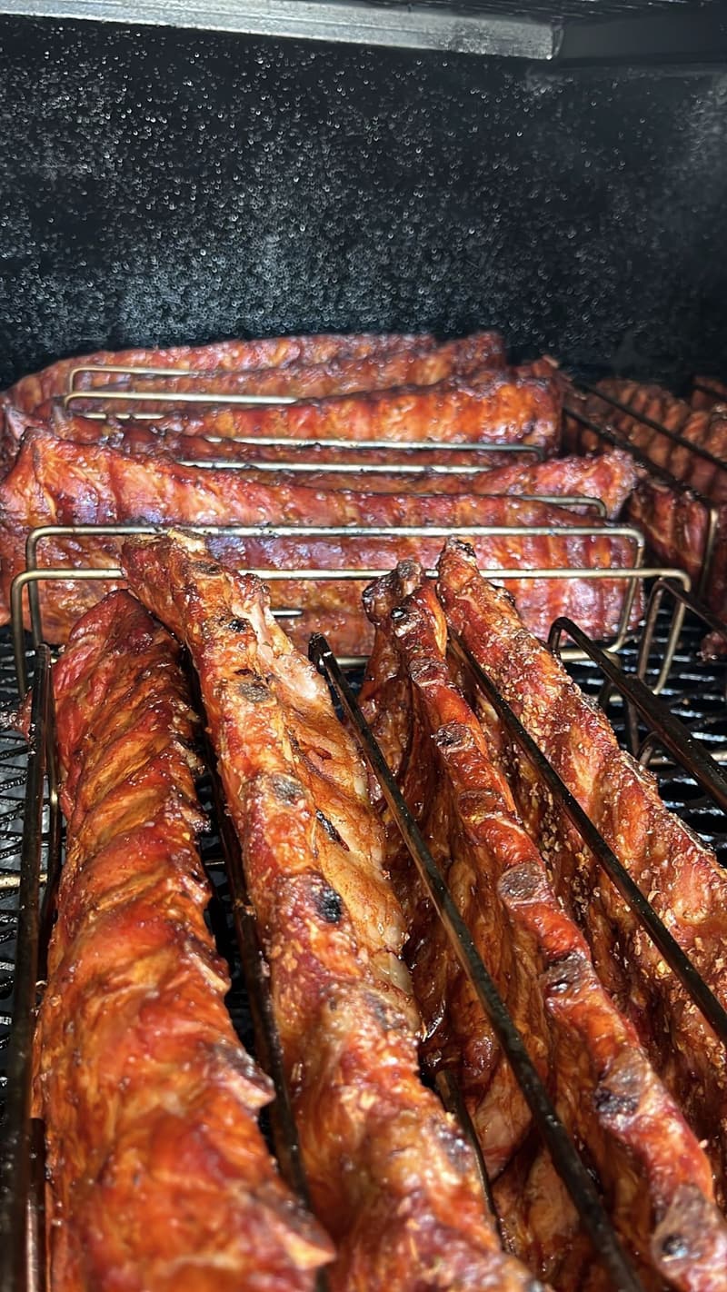 Close-up of sticky, glazed ribs lined up on the smoker racks.