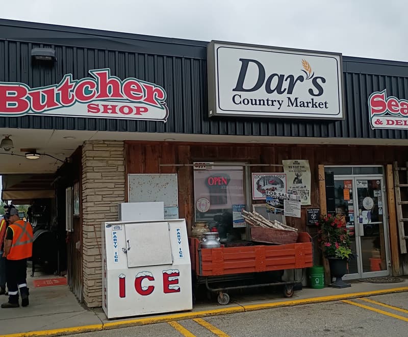 Dar’s Country Market from the parking lot: the red Butcher Shop sign, the Dar’s sign, the Seafood sign and the ICE freezer by the door.